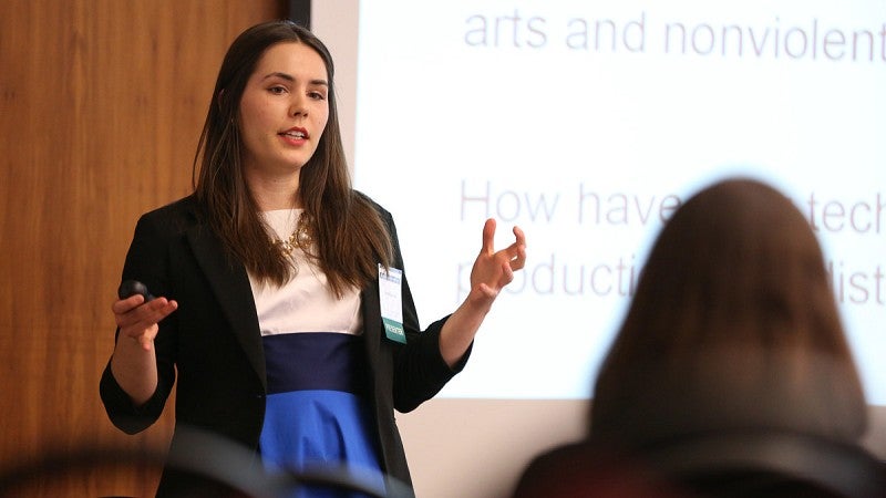 White, female student in professional attire gives a presentation.