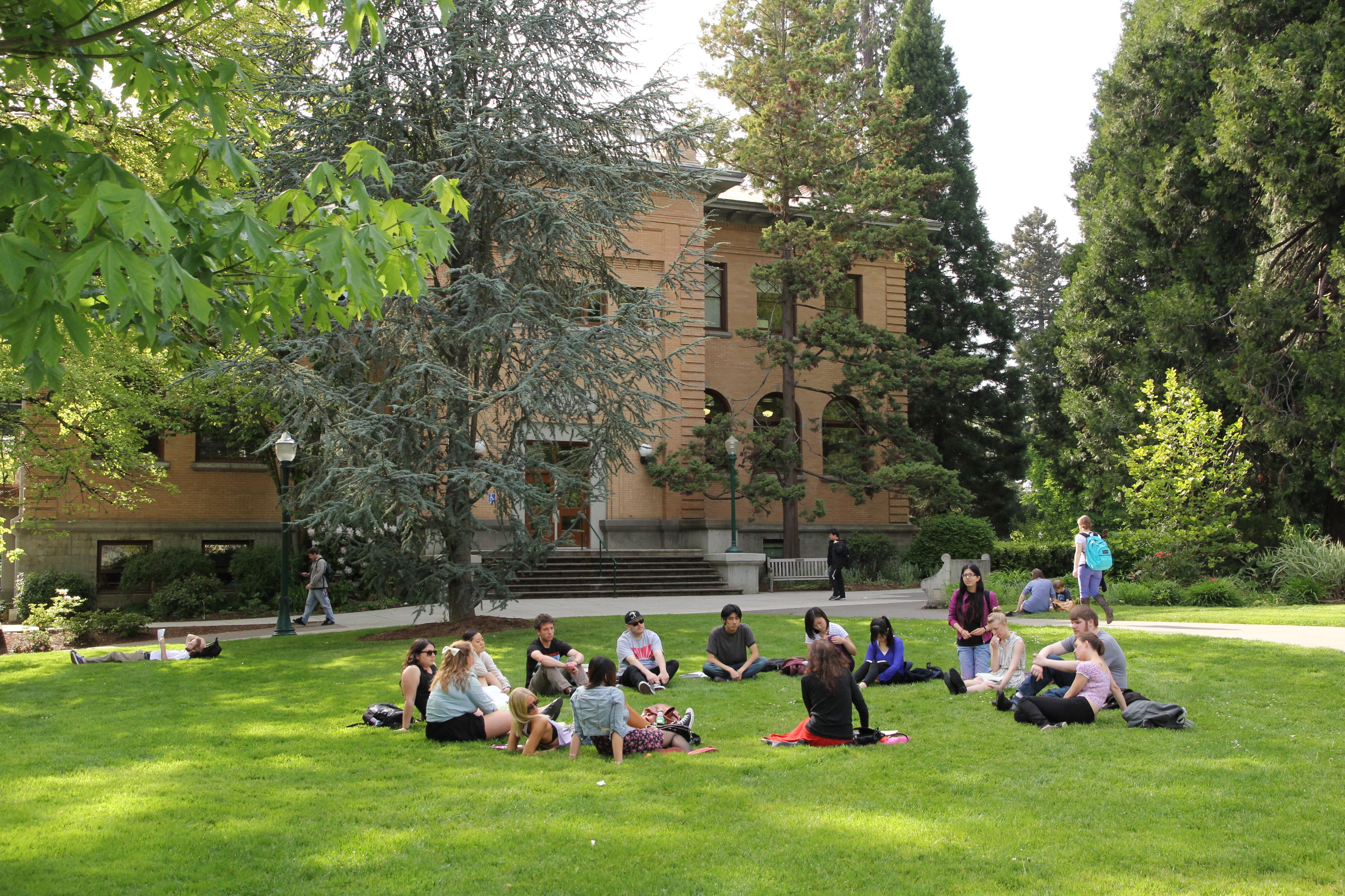 People sitting on the lawn outside of Fenton Hall on UO Campus