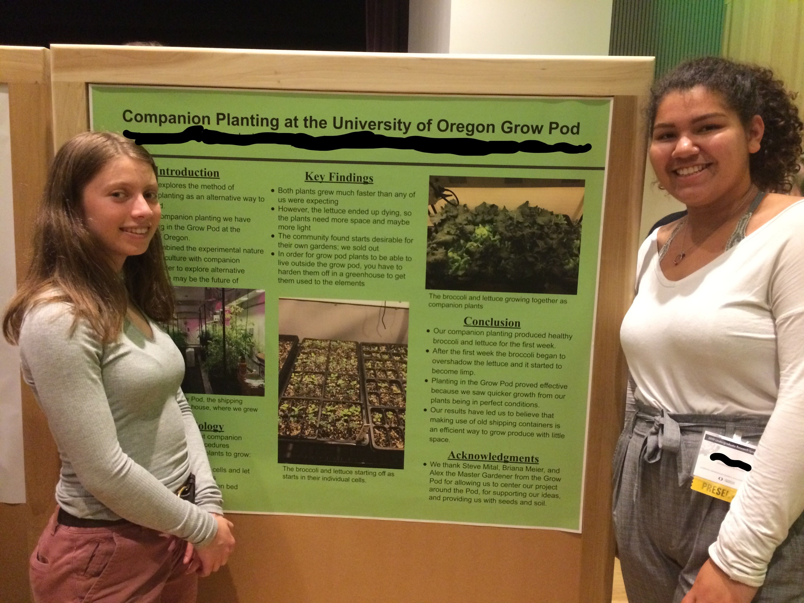 Young women standing in front of their Companion Planting research poster.