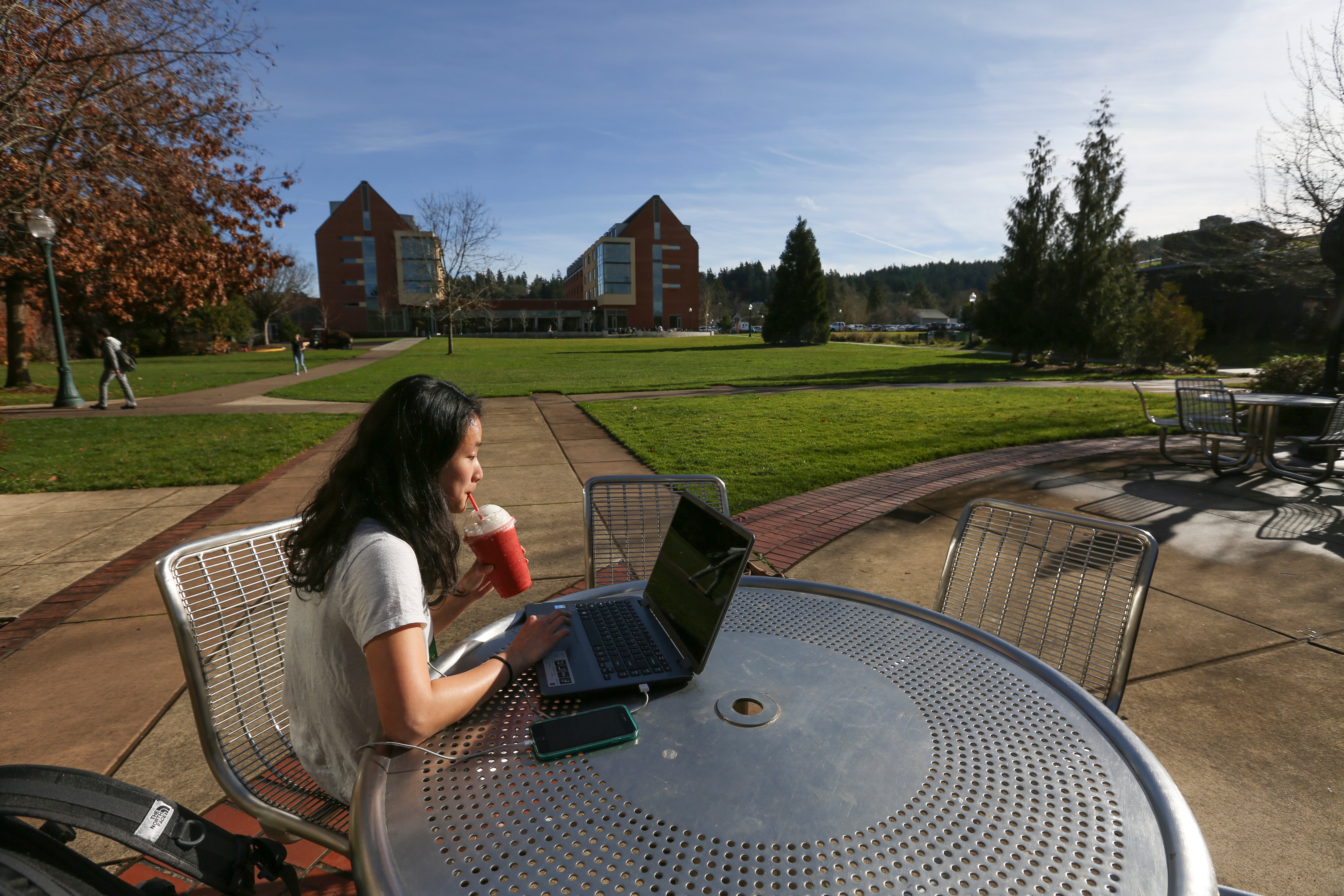 A student enjoys a fruit smoothy in the sunshine behind the Law School on Friday, Jan. 22, 2016, on the University of Oregon campus in Eugene, Oregon.