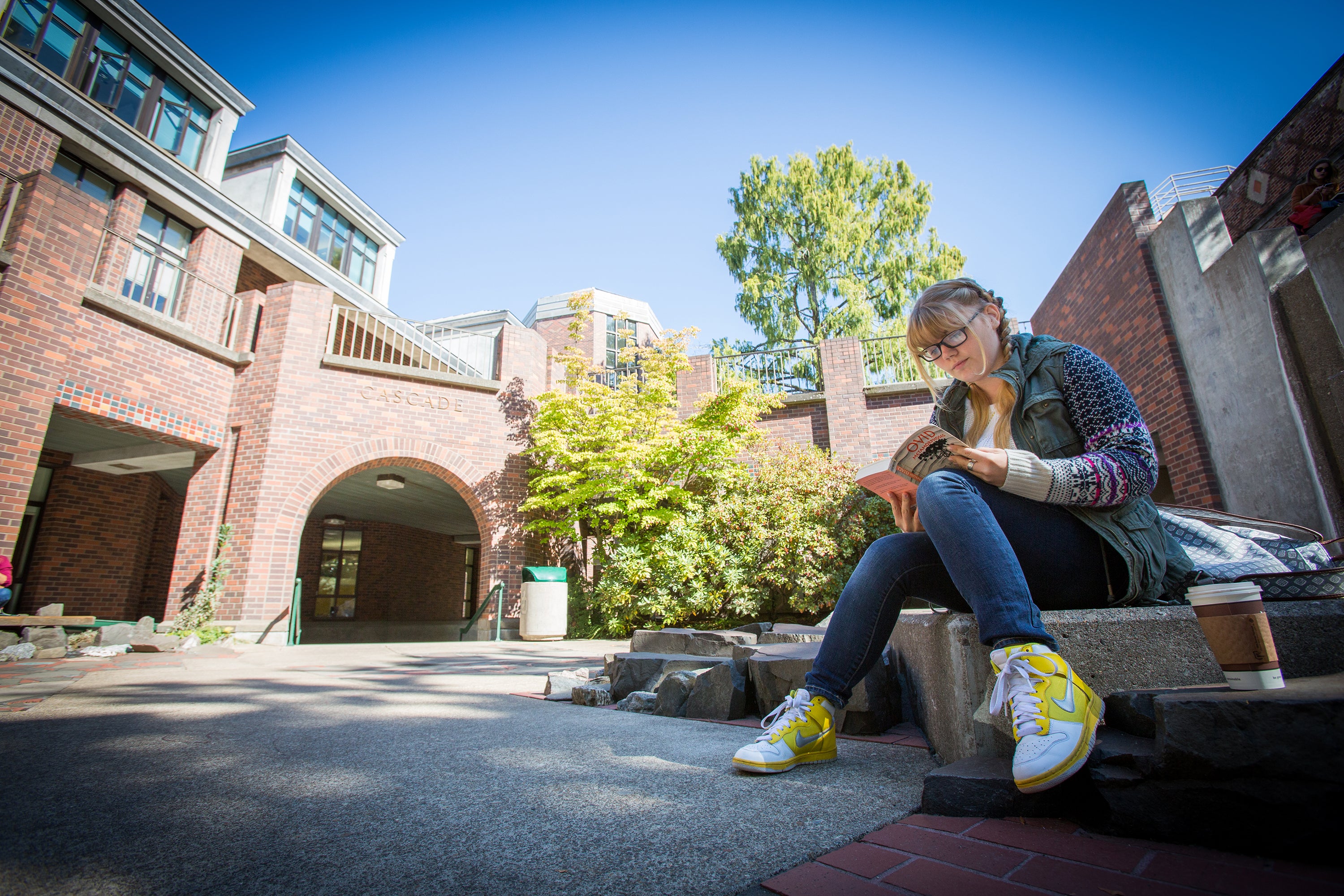 A white female student reads near a campus water feature.