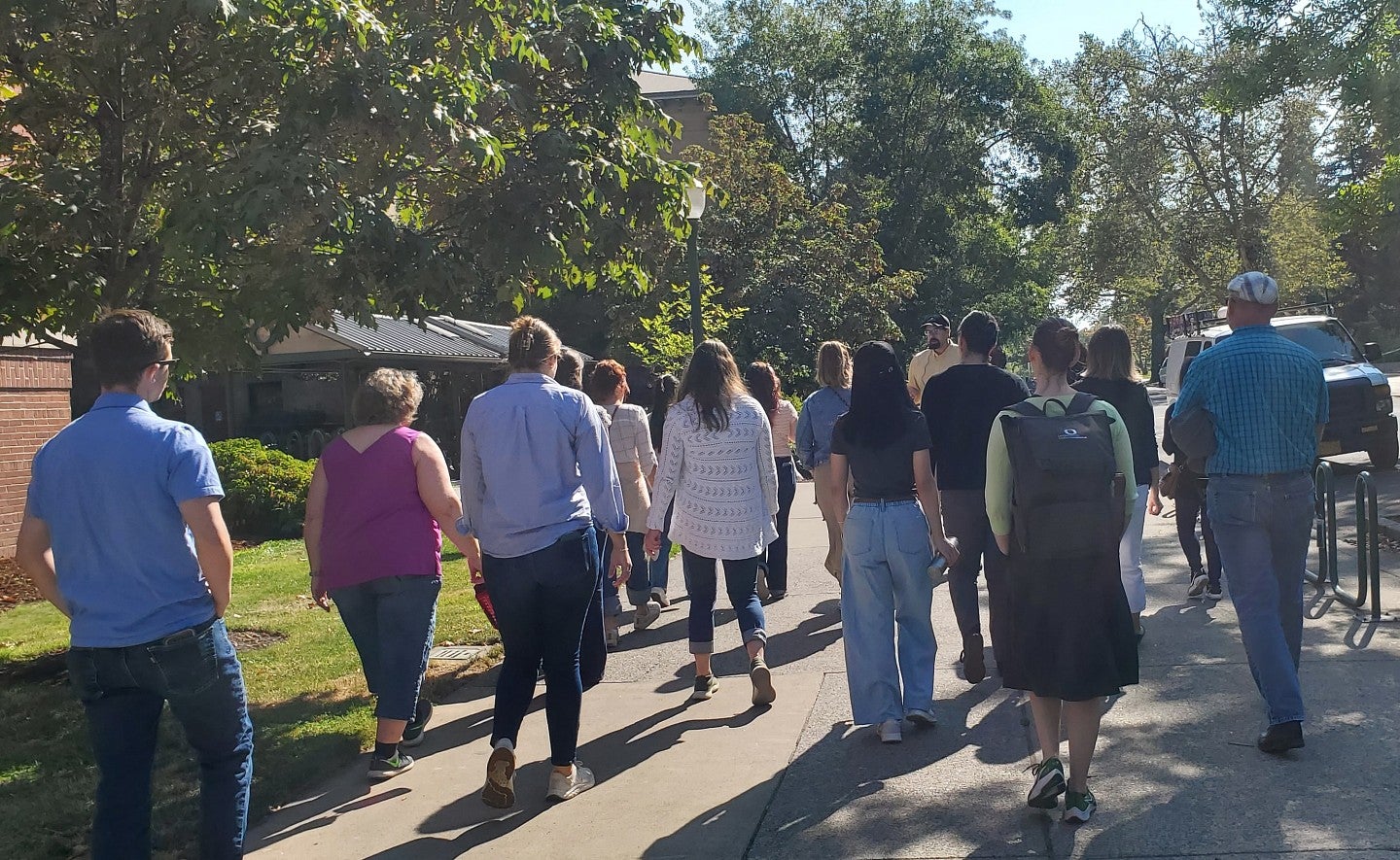 A group of people follow a tour guide on the University of Oregon campus.