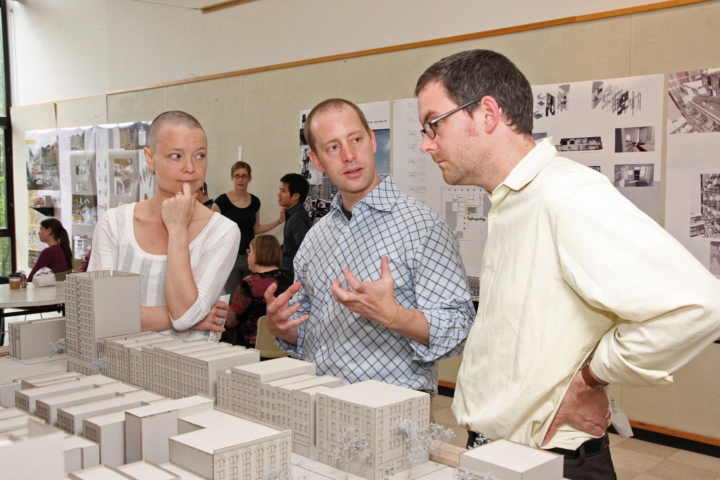 Faculty and students reviewing architectural designs and building models