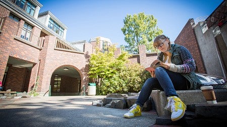 A white female student reads near a campus water feature.