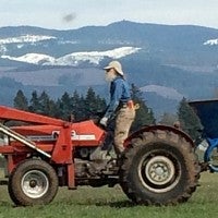 Photo of Energy Manager Boz Van Houten standing on a tractor with snowy hills in the background.